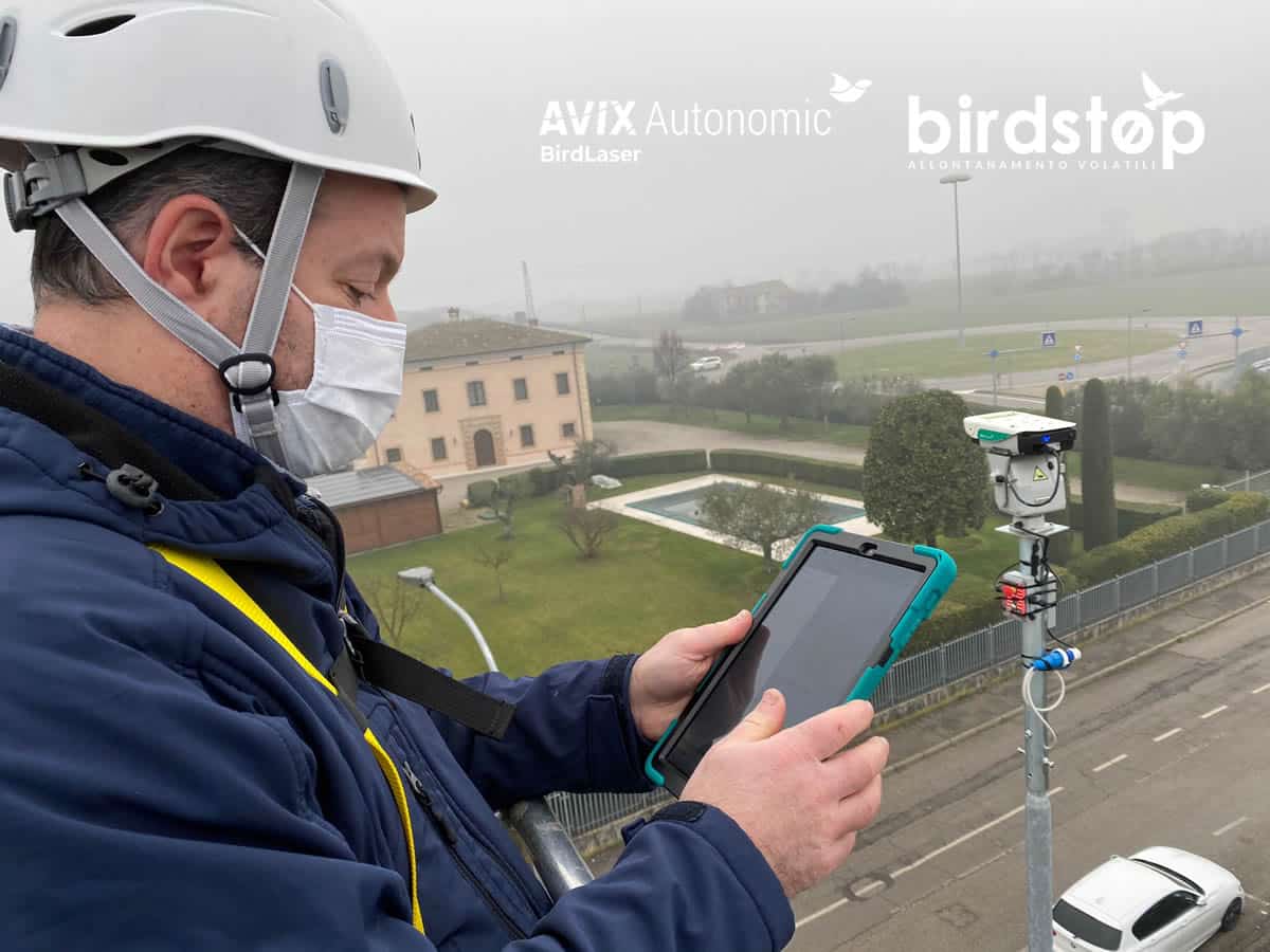 Tecnico con casco e tablet che configura in campo un impianto di dissuasione laser montato su palo