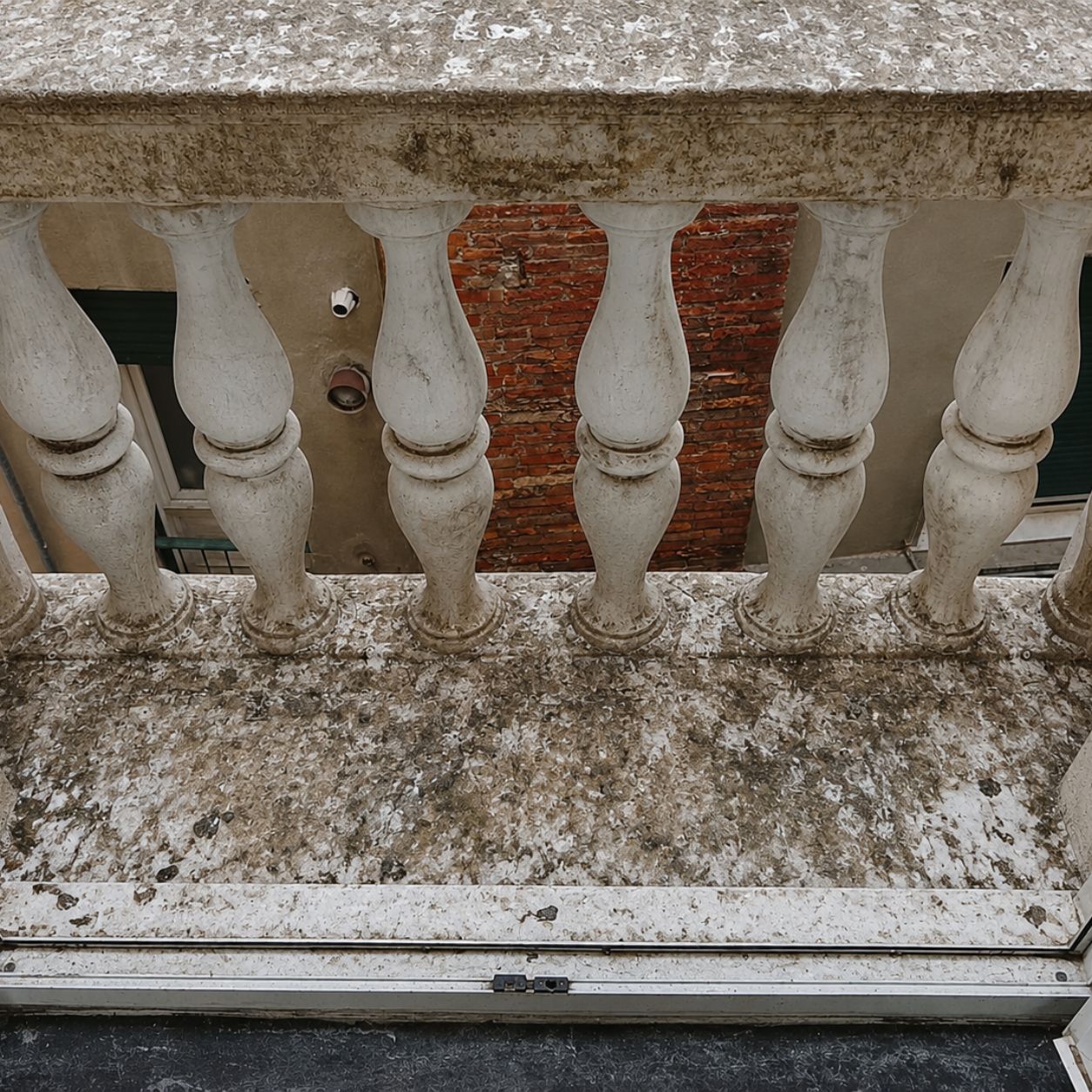 Balaustra in pietra di un edificio storico con il piano di appoggio incrostato di guano