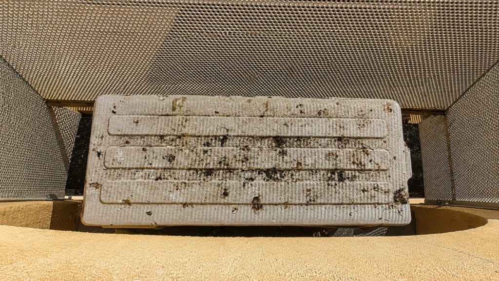 Griglia tecnica dentro un recinto di rete metallica con il piano superiore macchiato e striato di guano