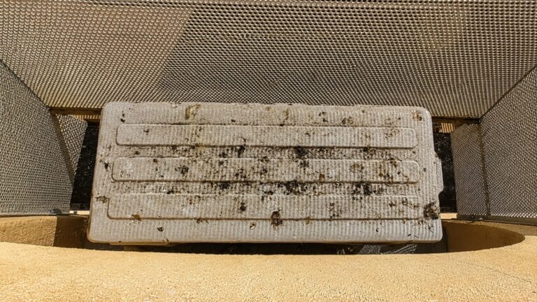 Griglia tecnica dentro un recinto di rete metallica con il piano superiore macchiato e striato di guano