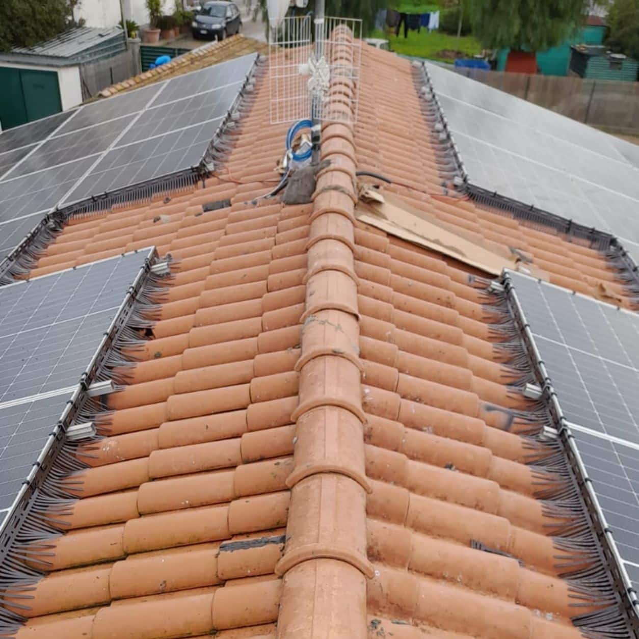 Colmo di un tetto residenziale con barriera installata fra i due campi fotovoltaici affiancati