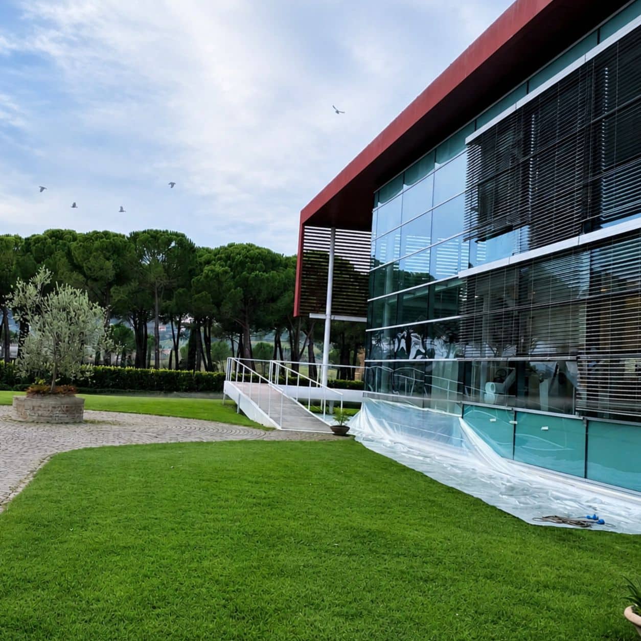 Rete anti volatili tesa sopra il portico vetrato di un edificio direzionale immerso nel verde