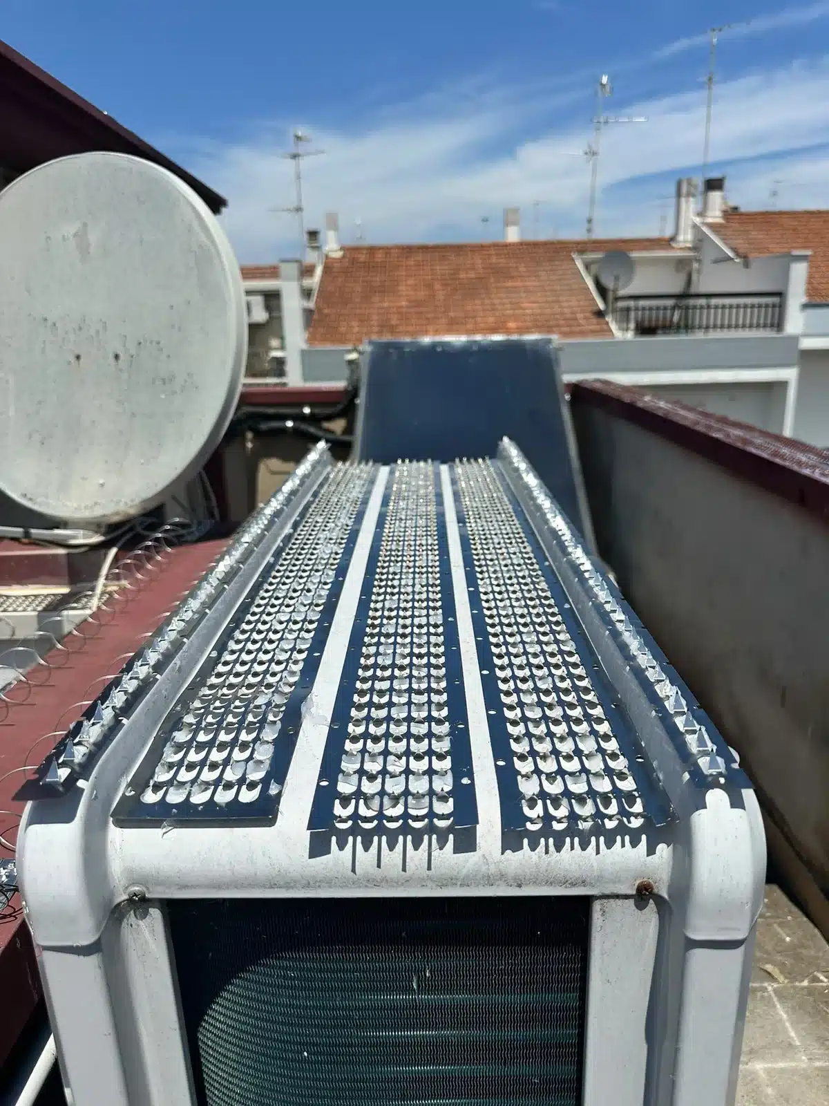 Pannello dissuasore in acciaio inox posato sul piano superiore di un’unità esterna di climatizzazione su una copertura