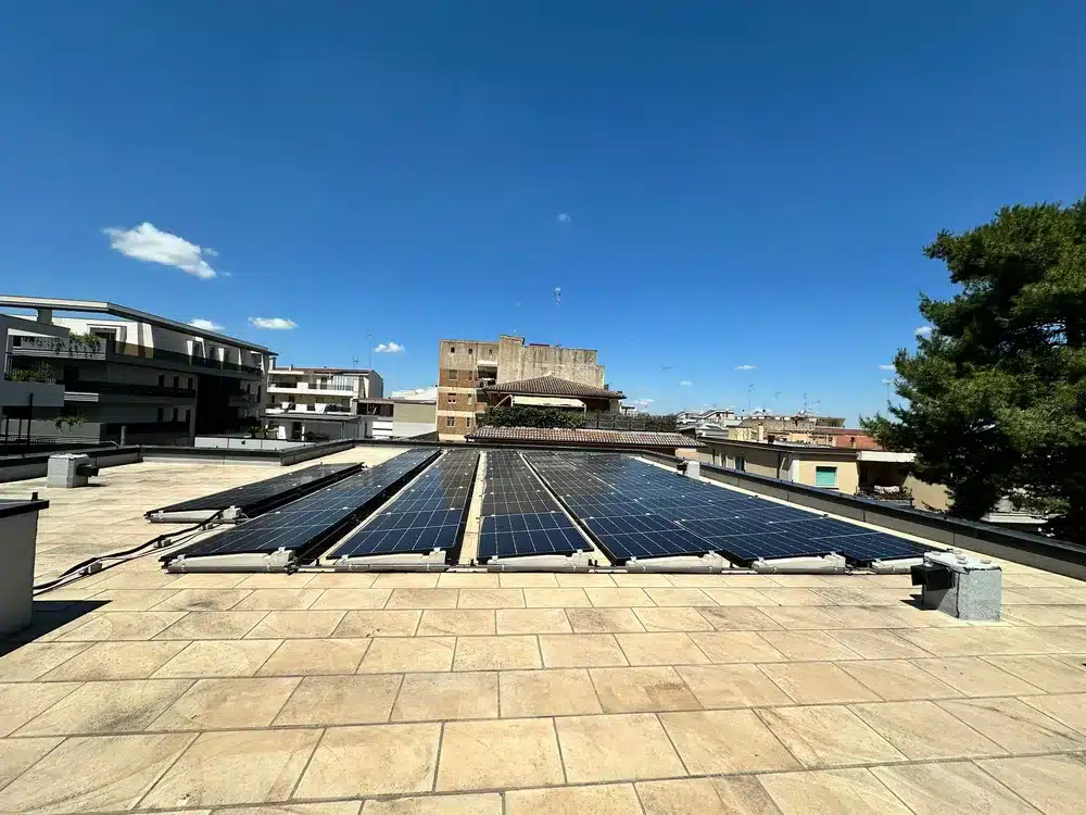 File parallele di moduli fotovoltaici su copertura piana a intervento concluso, viste in lunghezza