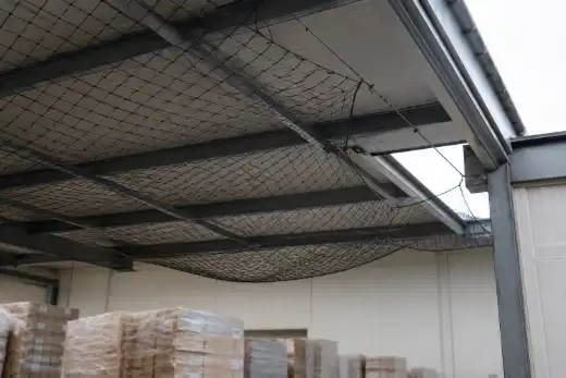 Rete anti-volatili allentata e con un varco aperto sotto la copertura di un capannone alimentare