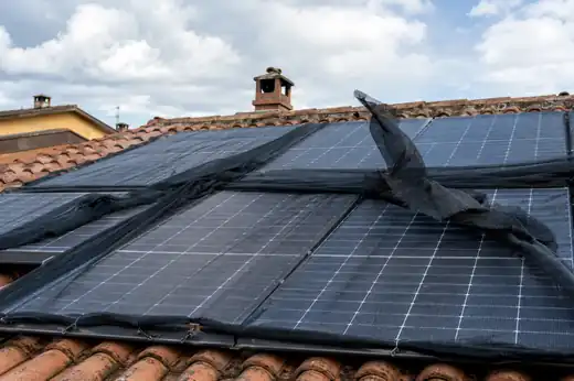 Rete antipiccioni allentata e strappata stesa sopra i pannelli fotovoltaici di un tetto