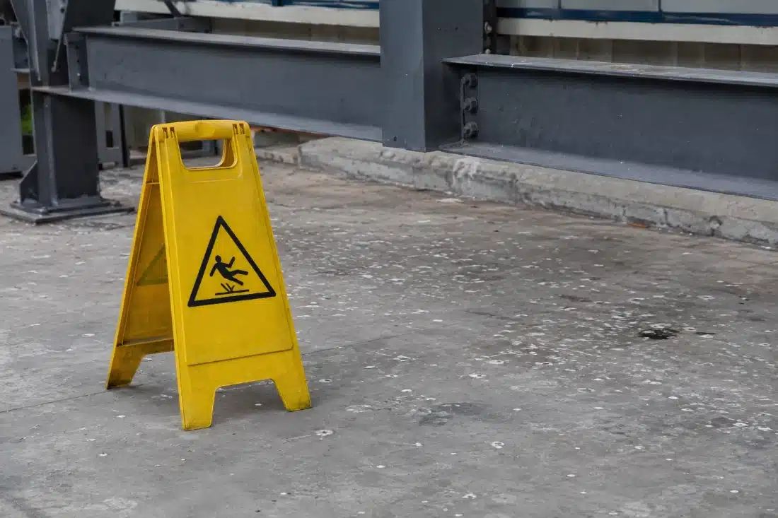 Cartello giallo di pavimento scivoloso posato sotto una zona imbrattata da escrementi