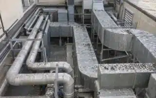 Piano tecnico sulla copertura di un edificio sanitario con tubazioni coibentate e canali dell&rsquo;aria in lamiera, coperti di guano e piume
