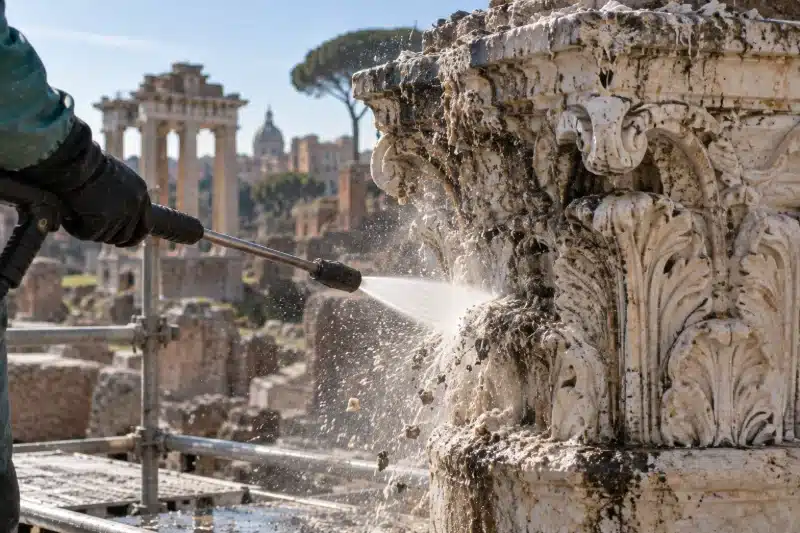 Getto di idropulitrice su un capitello antico coperto di guano in un'area archeologica