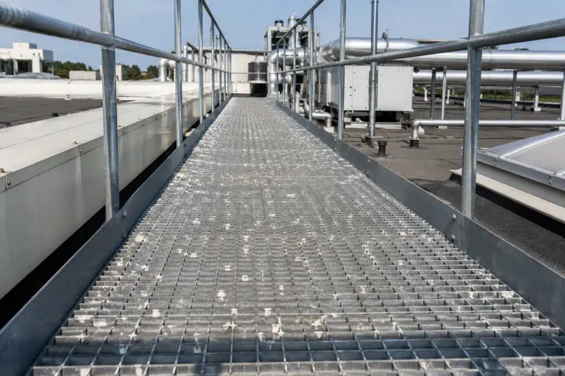 Camminamento in grigliato metallico sotto la copertura di un capannone, con tracce di guano