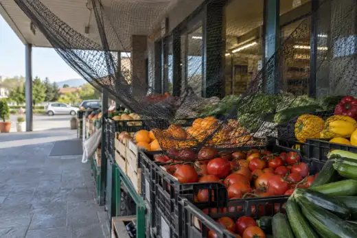 Rete anti-volatili nera tesa male e lasciata cadere sopra le cassette di frutta e verdura esposte davanti a un supermercato