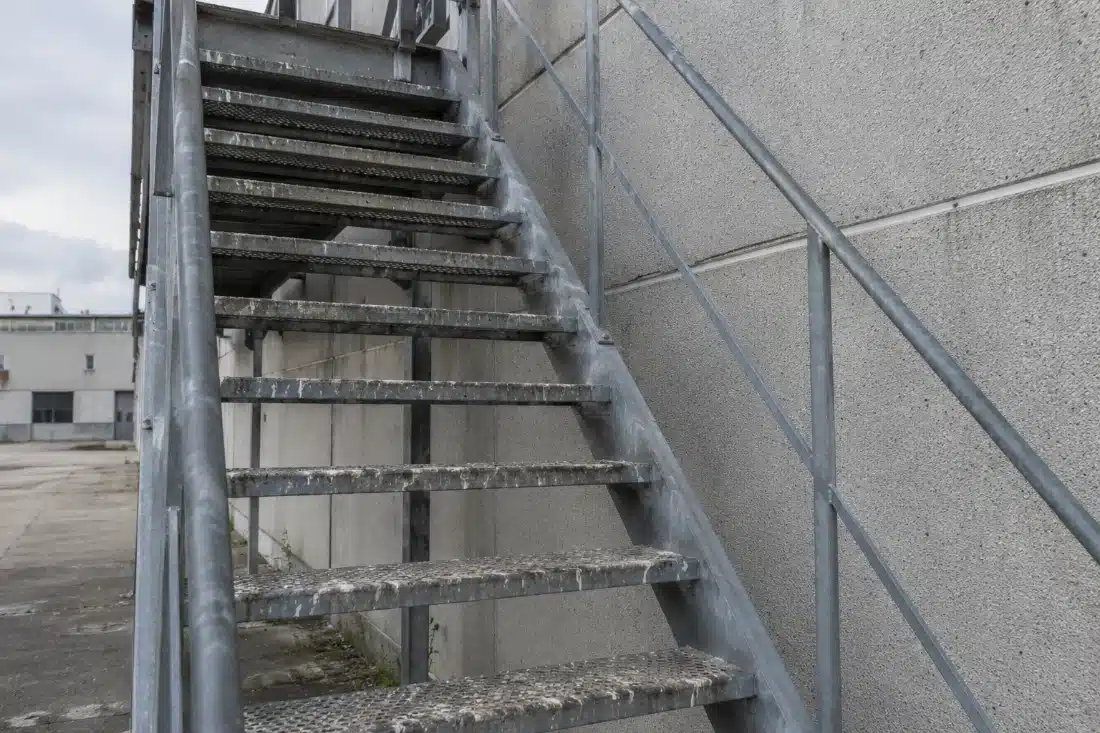 Scala metallica esterna di uno stabilimento con i gradini imbrattati di escrementi