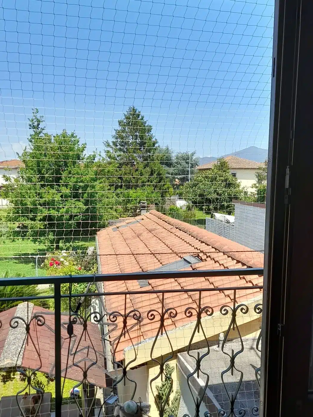Rete anti piccioni installata su un balcone, vista sul giardino