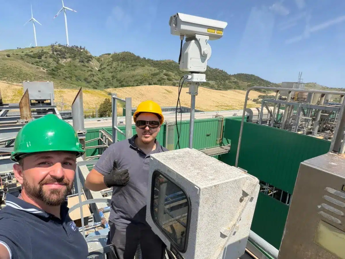 Due tecnici Ekonore accanto al dissuasore BirdLaser AI montato su palo in un impianto industriale