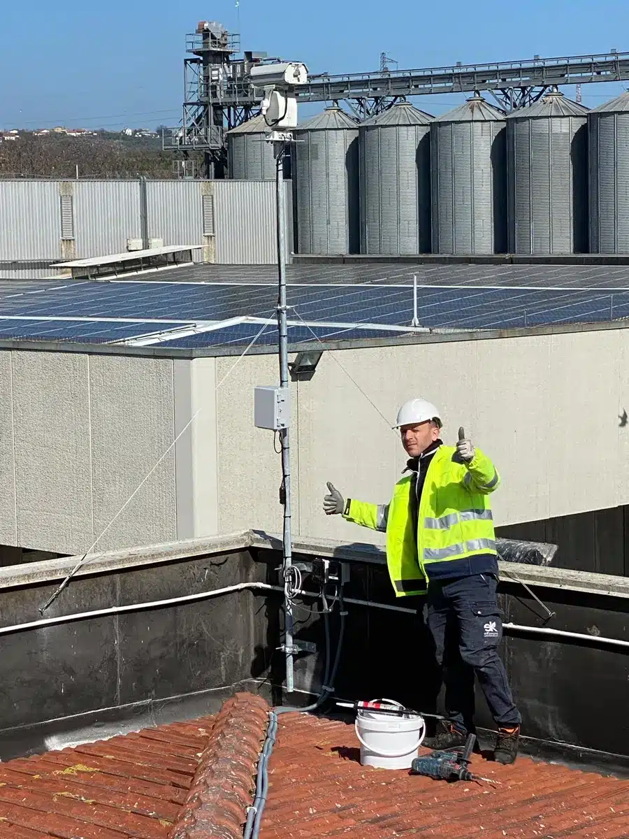 Tecnico Ekonore accanto al BirdLaser AI installato su palo davanti ai silos di uno stabilimento